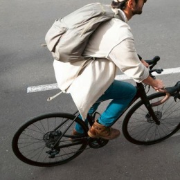 A man with a backpack riding a bike on the road.