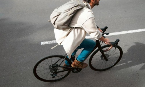 A man with a backpack riding a bike on the road.